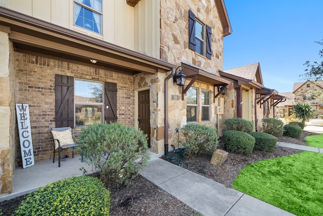 property entrance with board and batten siding, stone siding, and brick siding