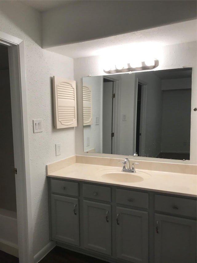 bathroom with a textured wall and vanity