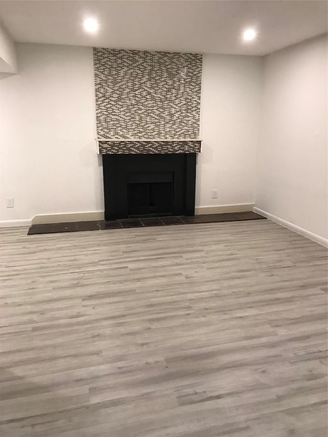 room details featuring a tile fireplace, recessed lighting, baseboards, and wood finished floors