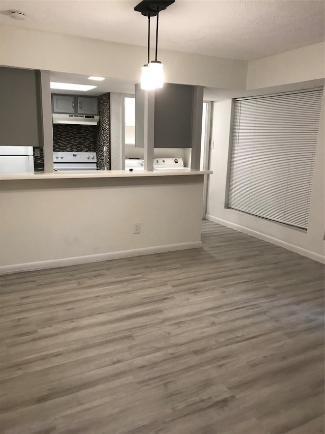 kitchen with stove, under cabinet range hood, baseboards, and wood finished floors