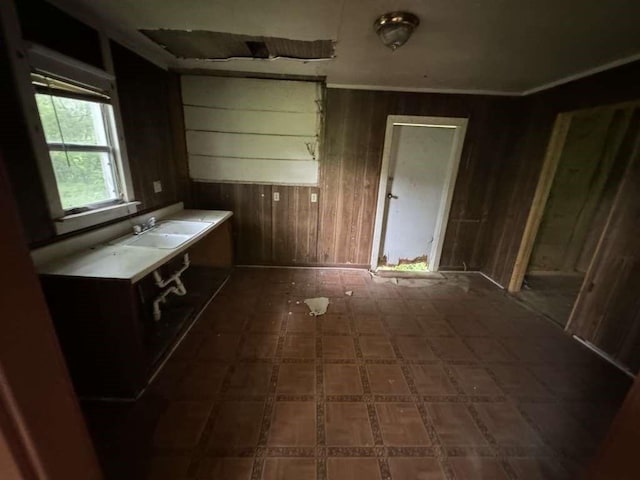 interior space with crown molding, tile patterned floors, a sink, and wooden walls