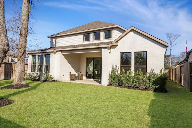 back of house featuring brick siding, a fenced backyard, a lawn, and a patio area