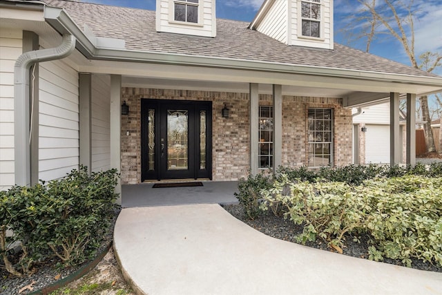 property entrance with a porch, a garage, brick siding, and roof with shingles