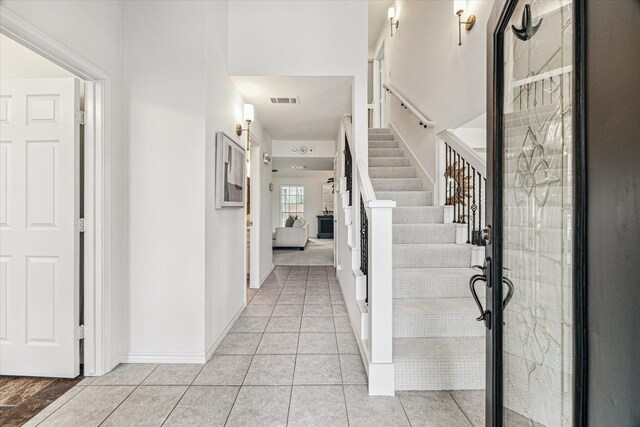 foyer featuring light tile patterned floors, visible vents, baseboards, and stairs