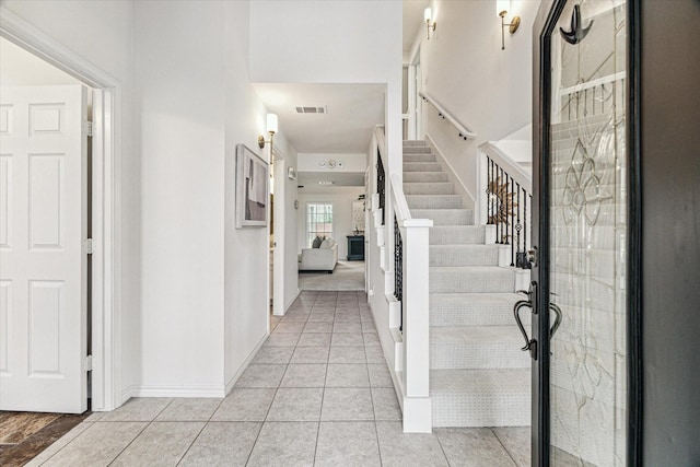 foyer with baseboards, visible vents, stairs, and light tile patterned floors