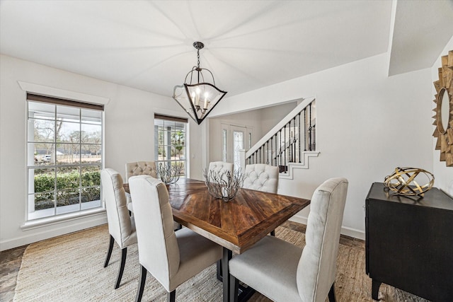 dining room featuring a notable chandelier, stairway, and baseboards