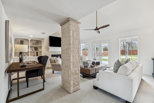 carpeted living area featuring visible vents, vaulted ceiling, french doors, a fireplace, and ornate columns