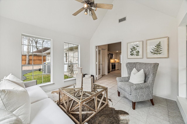 living area with plenty of natural light, baseboards, visible vents, and high vaulted ceiling