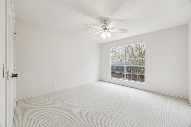 carpeted empty room featuring a ceiling fan and baseboards