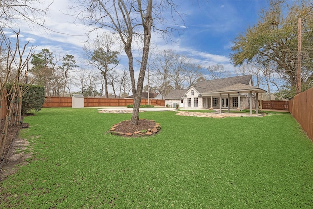 view of yard with a ceiling fan, a fenced backyard, driveway, an outdoor structure, and a patio