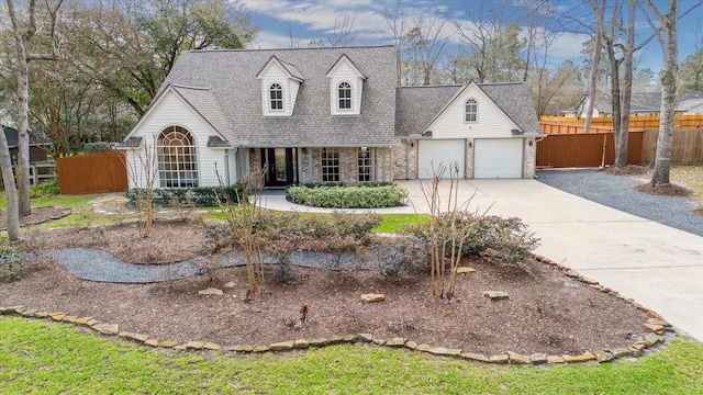 cape cod house featuring driveway, stone siding, fence, roof with shingles, and a garage