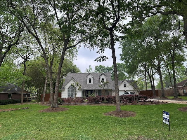 cape cod home featuring a front lawn and fence