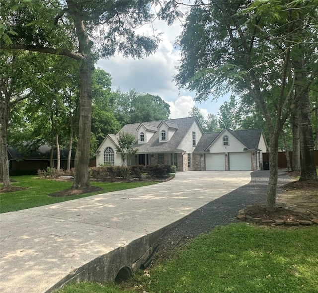 cape cod-style house featuring an attached garage, driveway, stone siding, and a front lawn
