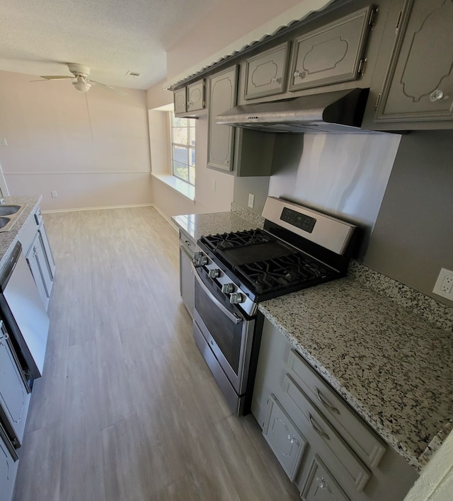 kitchen featuring gas stove, gray cabinets, and under cabinet range hood