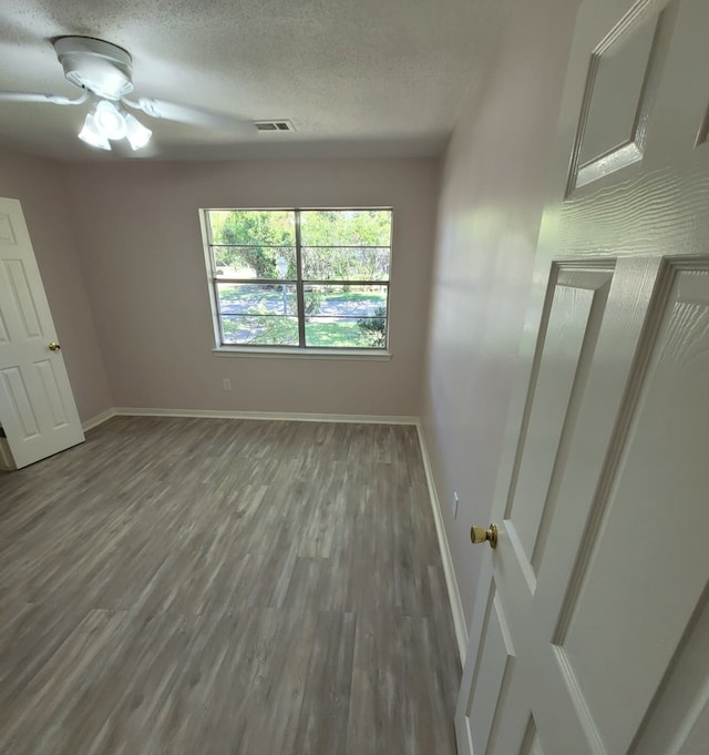 unfurnished bedroom with baseboards, visible vents, a textured ceiling, and wood finished floors