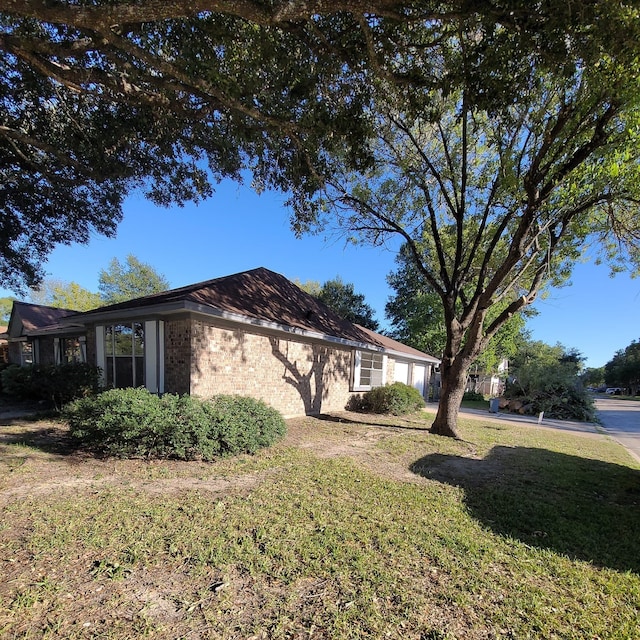 view of property exterior featuring an attached garage, a lawn, and brick siding