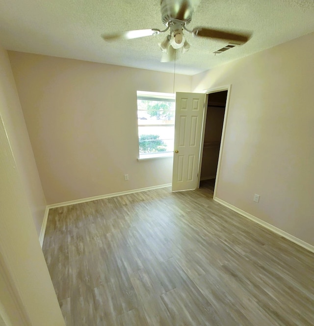 unfurnished bedroom featuring light wood-type flooring, visible vents, a textured ceiling, and baseboards