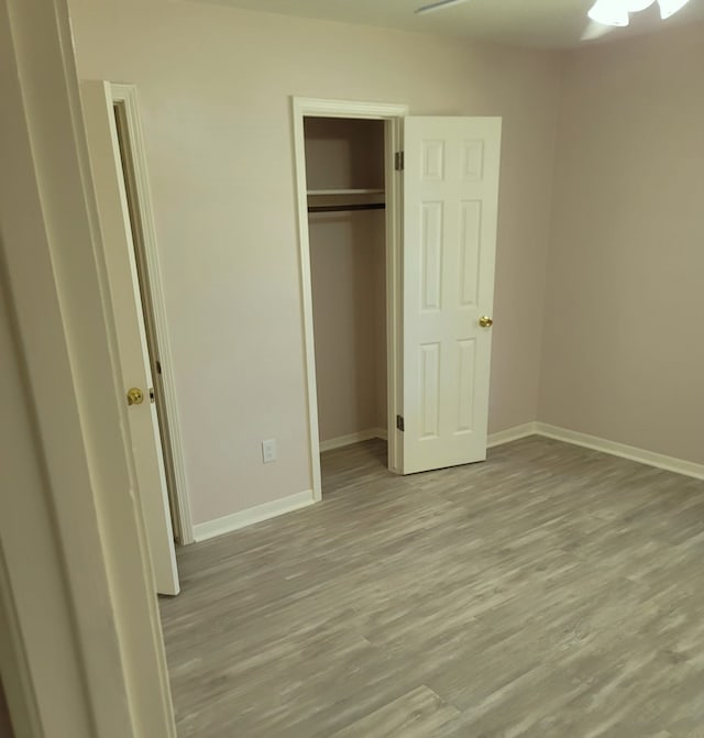 unfurnished bedroom with a closet, wood finished floors, and baseboards