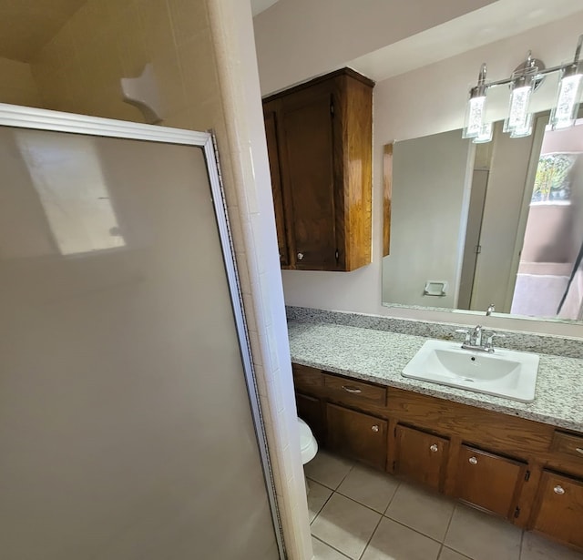 bathroom featuring toilet, a stall shower, vanity, and tile patterned floors