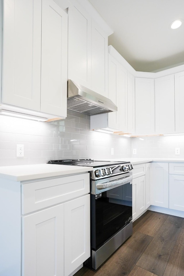 kitchen with dark wood-type flooring, stainless steel electric range, light countertops, backsplash, and exhaust hood