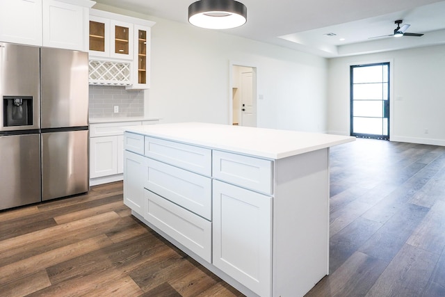 kitchen with a tray ceiling, backsplash, stainless steel fridge, and dark wood finished floors