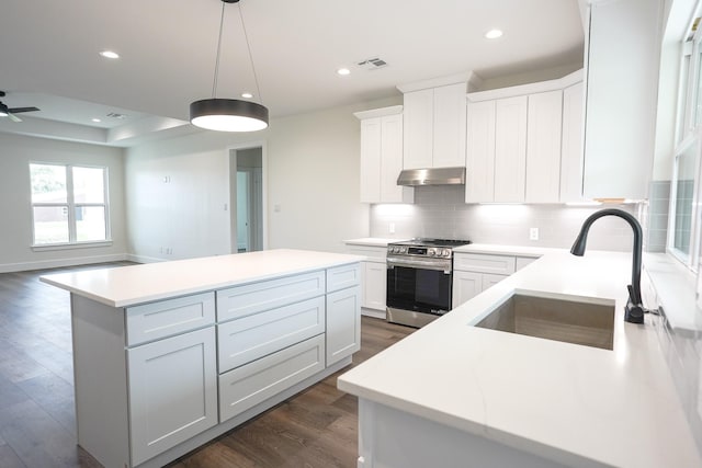 kitchen featuring a center island, visible vents, a sink, under cabinet range hood, and stainless steel electric range