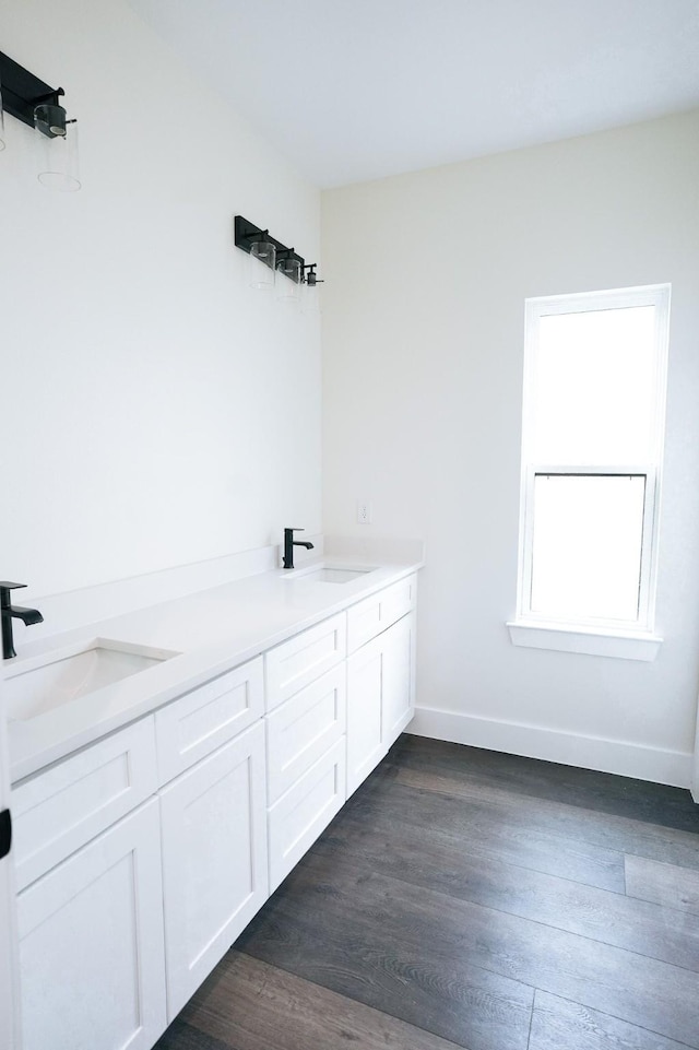 full bath with a sink, baseboards, and wood finished floors