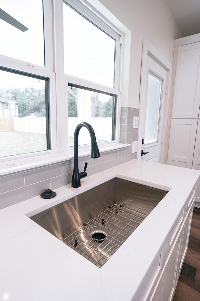 details with light stone countertops, white cabinetry, dark wood-type flooring, and a sink