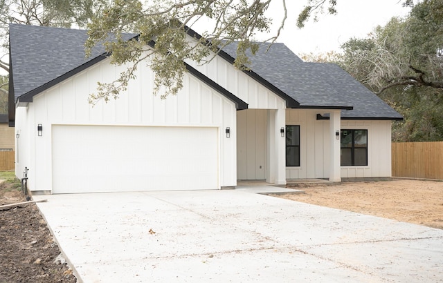 modern inspired farmhouse with an attached garage, board and batten siding, and roof with shingles