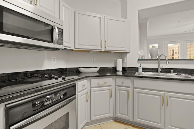 kitchen featuring light tile patterned flooring, a sink, white cabinets, ornamental molding, and appliances with stainless steel finishes