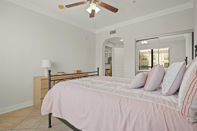 bedroom with light tile patterned floors, baseboards, visible vents, arched walkways, and ornamental molding