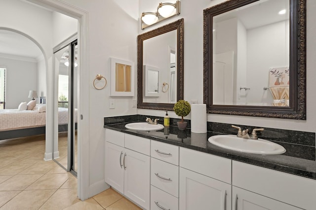 ensuite bathroom featuring tile patterned flooring, ornamental molding, a sink, and ensuite bathroom