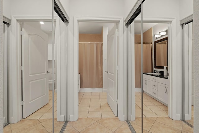 hall featuring light tile patterned flooring and a sink