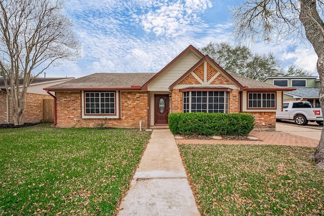 view of front facade featuring brick siding, a front yard, fence, and a shingled roof