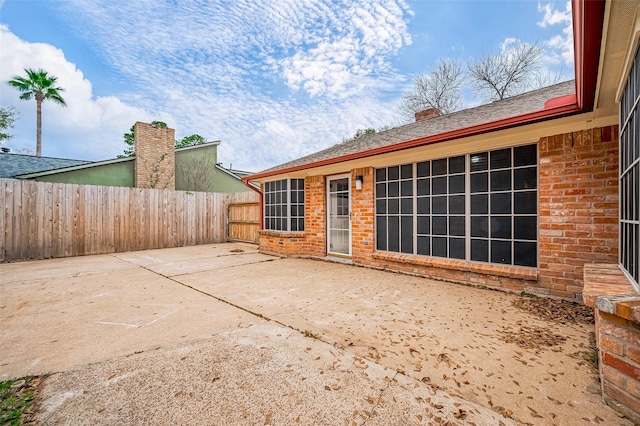 rear view of house with a patio area, a chimney, fence, and brick siding