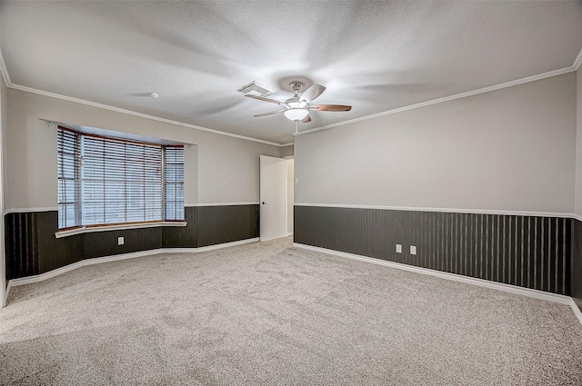 unfurnished room with visible vents, a wainscoted wall, ceiling fan, and a textured ceiling