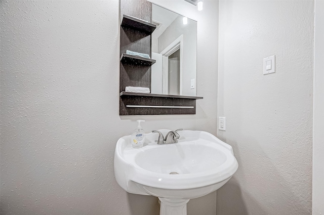 bathroom featuring a textured wall and a sink