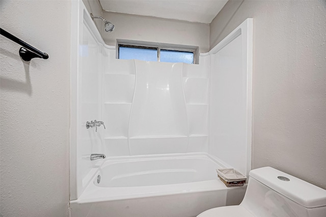 full bathroom featuring a textured wall, tub / shower combination, and toilet