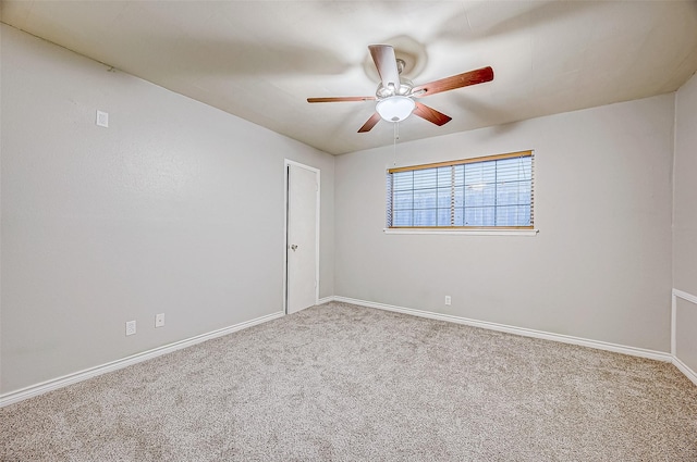 carpeted spare room featuring a ceiling fan and baseboards