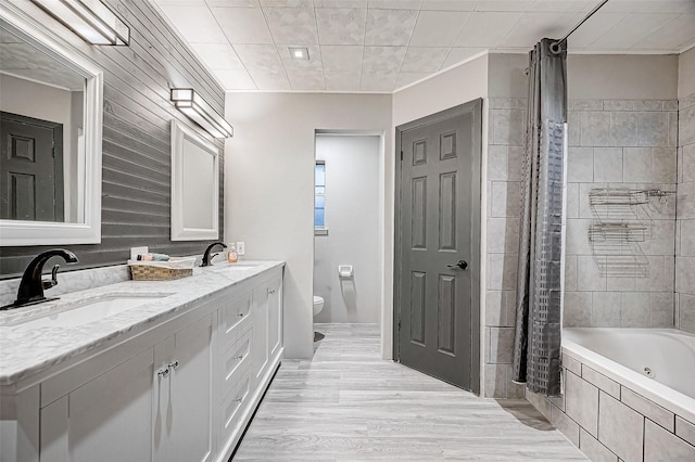 full bath with toilet, double vanity, a sink, and wood finished floors