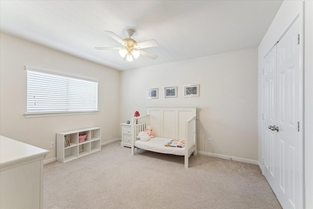 bedroom featuring light carpet, a ceiling fan, baseboards, and a closet