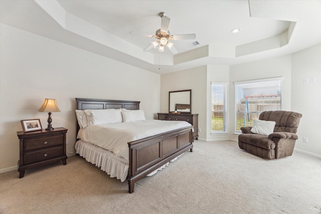 bedroom featuring a tray ceiling, visible vents, a ceiling fan, light carpet, and baseboards