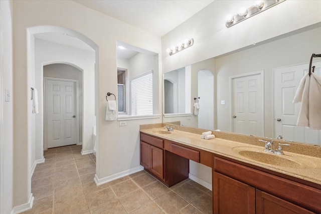 full bath featuring tile patterned flooring, a sink, baseboards, and double vanity