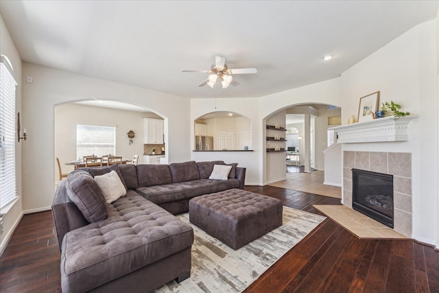 living area featuring hardwood / wood-style flooring, ceiling fan, a fireplace, and baseboards