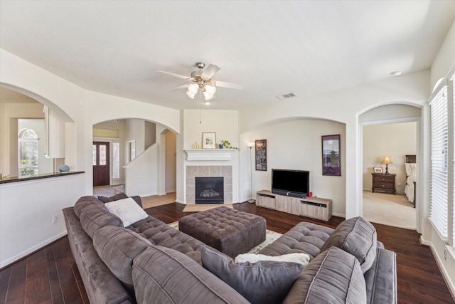 living area featuring a healthy amount of sunlight, baseboards, dark wood-style flooring, and a tile fireplace