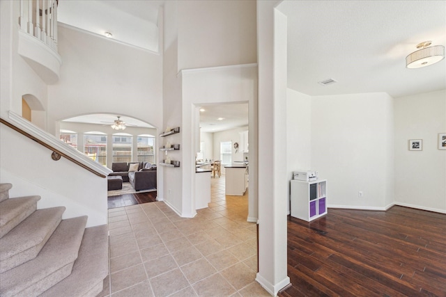 entryway with arched walkways, stairway, wood finished floors, and visible vents