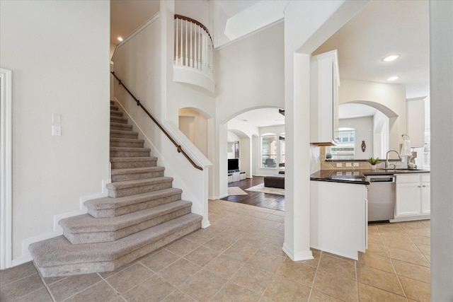 entrance foyer with a towering ceiling, recessed lighting, stairs, and light tile patterned flooring