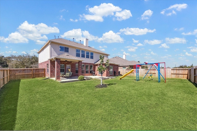 rear view of property featuring a lawn, a patio, a fenced backyard, a playground, and brick siding