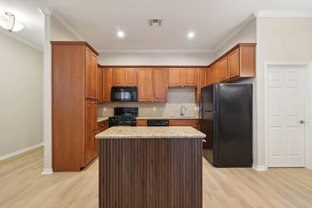 kitchen featuring a kitchen island, a sink, light wood-type flooring, black appliances, and backsplash