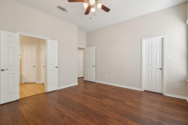 unfurnished bedroom featuring a ceiling fan, dark wood-style flooring, visible vents, and baseboards